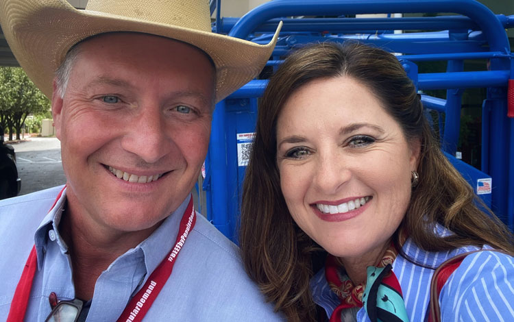 Roger and Nikki Callison of Callison Ranch beef wearing blue shirts and posing in front of a blue fence.